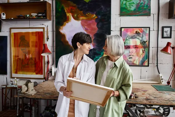 Two mature lesbian women standing in an art studio. — Stock Photo