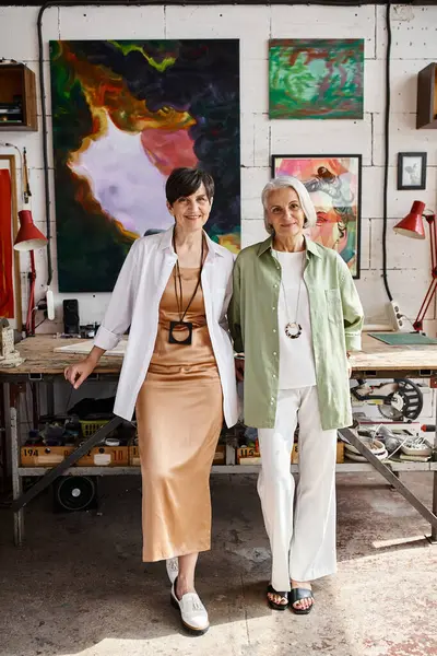 Dos mujeres maduras de pie pacíficamente en un estudio de arte. - foto de stock