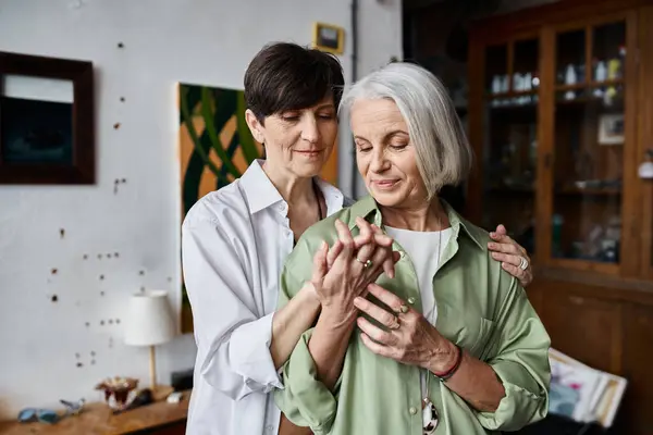 A mature lesbian couple are standing in artsy room. — Stock Photo