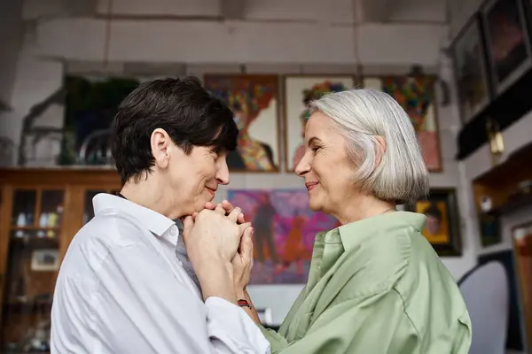A mature lesbian couple standing together in an art studio. — Stock Photo