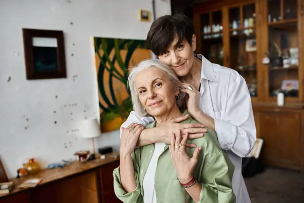 Two mature women hugging in an art studio. — Stock Photo