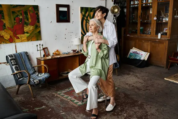 A mature lesbian couple in an art studio, standing together. — Stock Photo