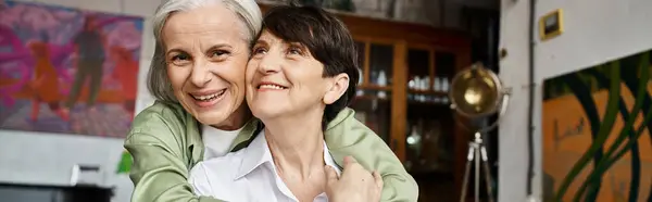 Cheerful woman embraces brunette woman in a warm setting. — Stock Photo