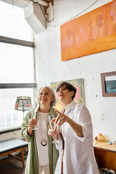 Una coppia lesbica matura in piedi insieme in uno studio d'arte. — Foto stock