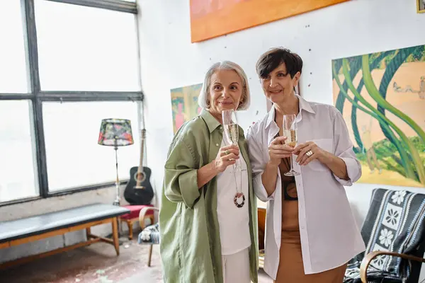 A mature lesbian couple in an art studio, standing close together. — Stock Photo