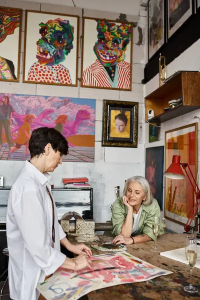 Maduro casal lésbico analisando obras de arte em estúdio. — Fotografia de Stock