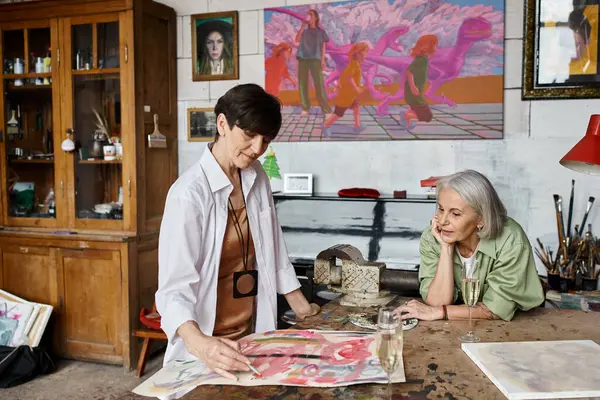 Two woman admire a painting in an art studio. — Stock Photo