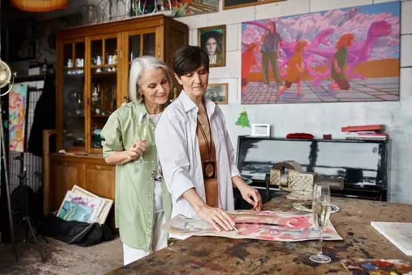 Mature lesbian couple standing in an art studio, sharing a tender moment. — Stock Photo