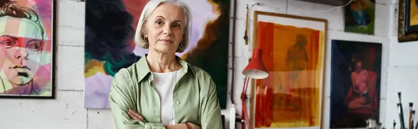 A woman standing in front of colorful paintings on a wall. — Stock Photo