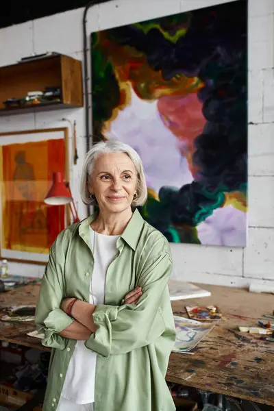 A woman standing before a captivating painting in an art studio. — Stock Photo