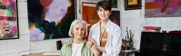 Due donne in piedi di fronte a dipinti in uno studio d'arte. — Foto stock