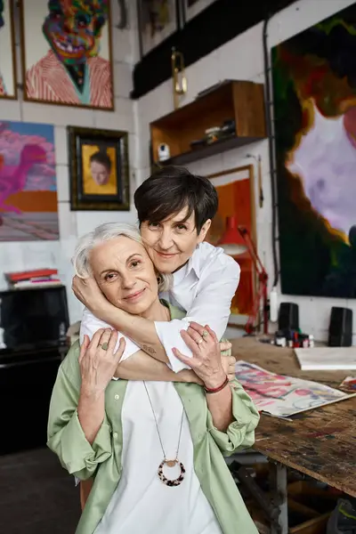 Zwei Frauen umarmen sich in einem gemütlichen Kunstatelier. — Stockfoto