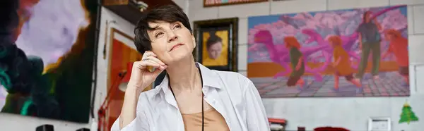 A woman in a white shirt posing near paintings. — Stock Photo