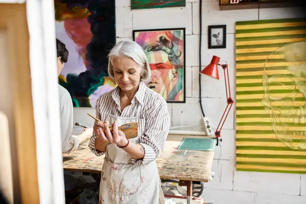 Mature woman intricately painting a picture. — Stock Photo