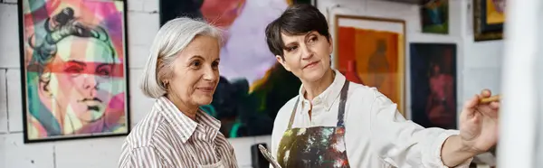 Due donne ammirano i dipinti in una galleria. — Foto stock