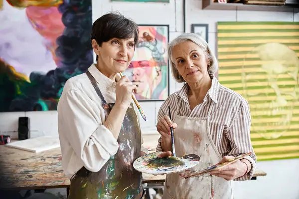 A woman holds a paintbrush next to her partner in an art studio. — Stock Photo