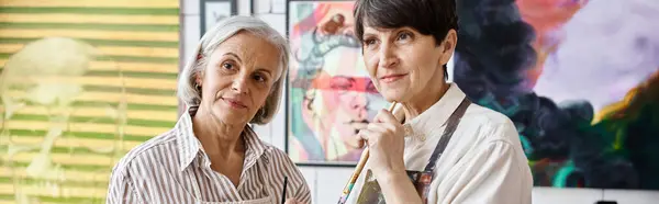 Two women stand in awe in front of a large painting in an art studio. — Stock Photo