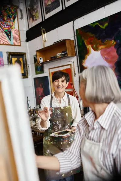 A mature lesbian couple working together in an art studio. — Stock Photo