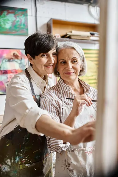 Una pareja de lesbianas maduras se encuentra lado a lado en un estudio de arte. — Stock Photo