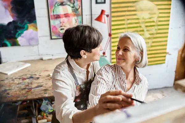 Duas mulheres envolvidas na visualização de uma pintura requintada em um estúdio de arte. — Fotografia de Stock