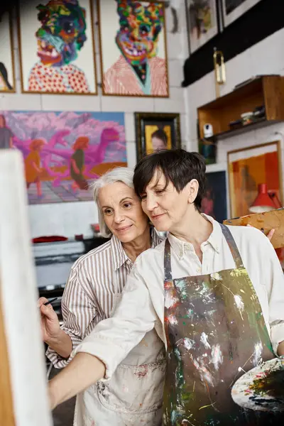 Two mature women, a lesbian couple, stand side by side in an art studio. — Stock Photo