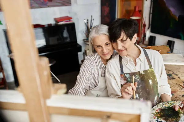 A mature lesbian couple sitting peacefully in an art studio. — Stock Photo