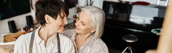 Mature lesbian couple standing together in art studio. — Stock Photo
