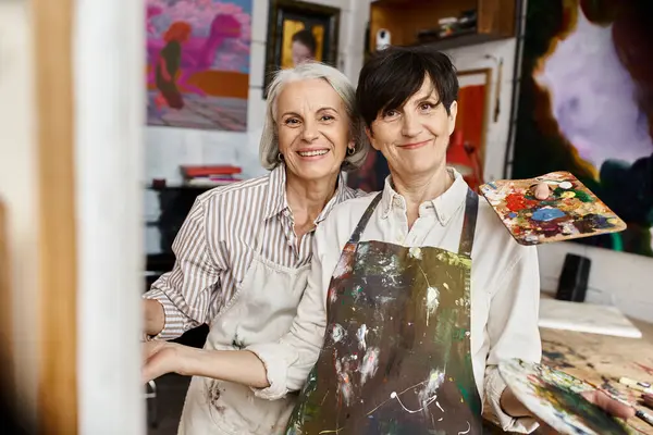 Mature lesbian couple enjoying a creative moment in an art studio. — Stock Photo