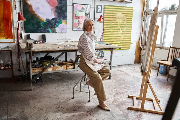 Woman sits on a chair in front of an easel, deep in thought and contemplation. — Stock Photo