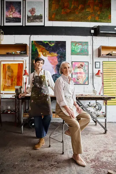 Two women admire paintings in an art studio. — Stock Photo