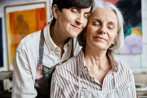 Two women lovingly huging each other in art studio. — Stock Photo