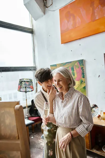 Due donne mature e innamorate, in piedi fianco a fianco in uno studio d'arte. — Foto stock