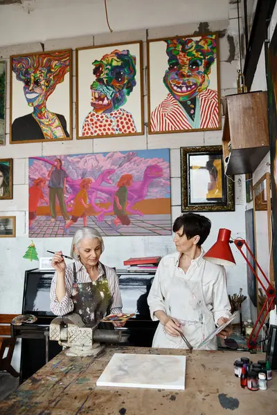 Due donne ammirare dipinti in ambiente accogliente studio d'arte. — Foto stock