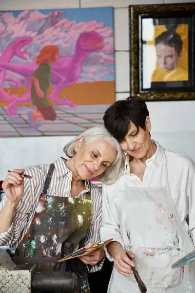 Deux femmes, couple lesbienne mature, debout dans un studio d'art. — Photo de stock