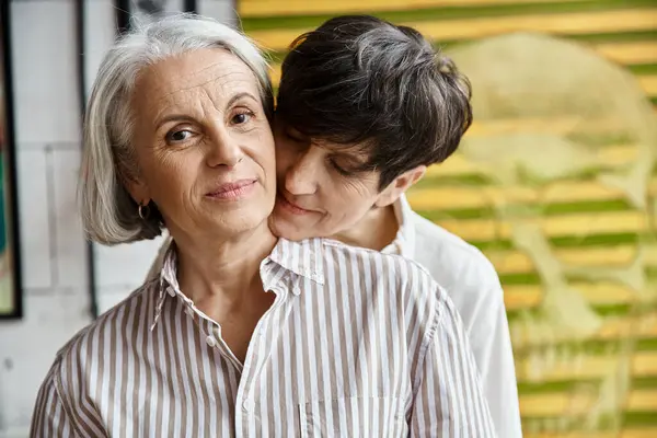 Two women embrace in front of a painting. — Stock Photo