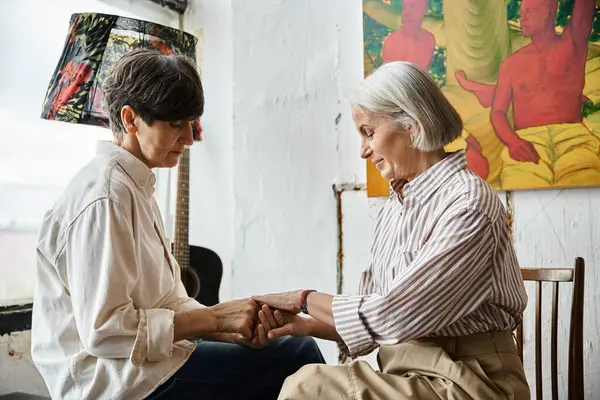 Dos mujeres cogidas de la mano en el estudio de arte. - foto de stock