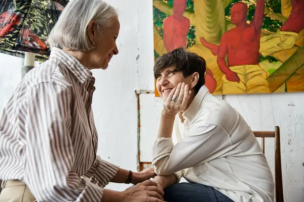 Two women sit together in an art studio, working on a project. — Stock Photo