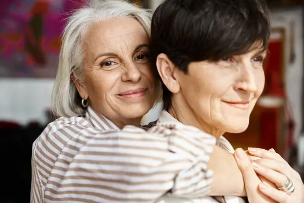 Two women hugging lovingly in an art studio. — Stock Photo