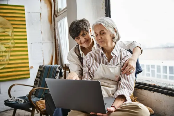 Two women interact with laptop screen in cozy setting. — Stock Photo