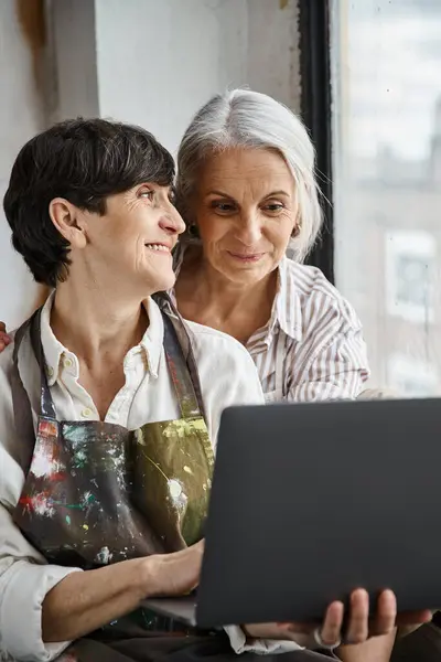 Two women engaged in work, focusing on laptop screen. — Stock Photo