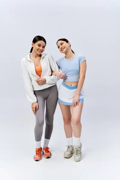 Dos chicas adolescentes guapas y morenas en traje deportivo, paradas una al lado de la otra, exudando confianza y vibraciones de amistad. — Stock Photo