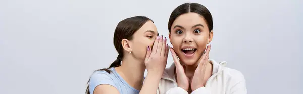 Two pretty, brunette teenage girls in sportive attire, making funny faces and gestures with their hands. — Stock Photo