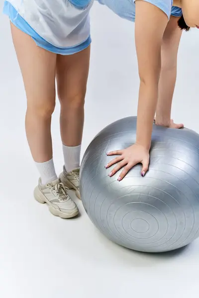 A pretty, brunette teenage girl in sportive attire gracefully balances on an exercise ball, showing strength and agility. — Stock Photo