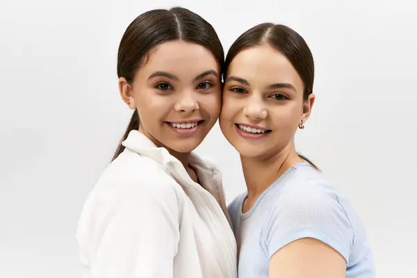 Дві красиві, брюнетка дівчата-підлітки в спортивному одязі, стоять поруч один з одним з обіймами в теплих обіймах. — стокове фото