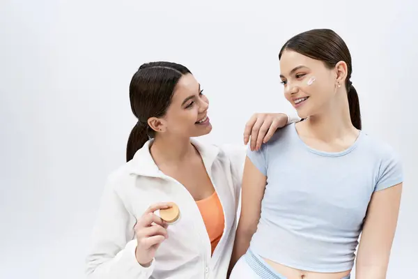 Дві молоді дівчата, красива і брюнетка, стоять разом у спортивному одязі, виключаючи впевненість і дружбу на сірому тлі. — стокове фото