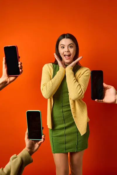 Brunette girl in green dress near cell phones in a vibrant setting. — Stock Photo