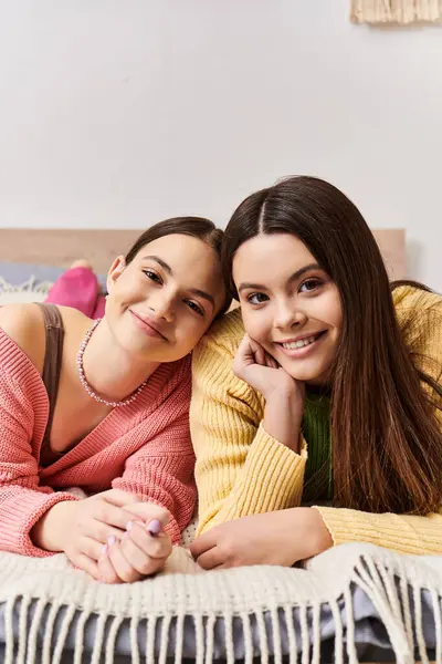Дві красиві дівчата-підлітки в повсякденному одязі розкладаються разом на ліжку, насолоджуючись компанією один одного в затишній обстановці. — стокове фото