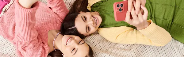 Zwei stylische junge Frauen in lässiger Kleidung liegen friedlich nebeneinander auf einem bequemen Bett zu Hause. — Stockfoto