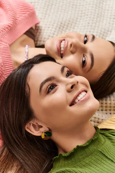 Two pretty teenage girls in casual attire embrace each other while laying on a bed, exuding tranquility and comfort. — Stock Photo