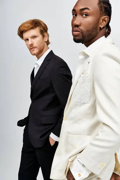 Два мультикультурных мужчины в стильных костюмах стоят рядом друг с другом. — стоковое фото